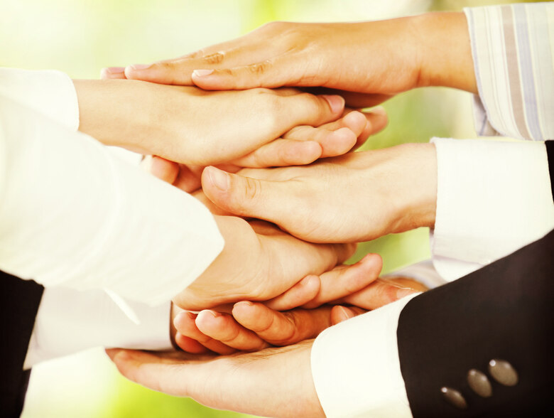 Hände liegen aufeinander, um Zusammenahlt zu symbolisieren.