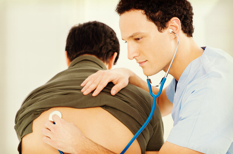 Ein ausländischer Art hört einen Patienten mit einem Stethoskop ab.